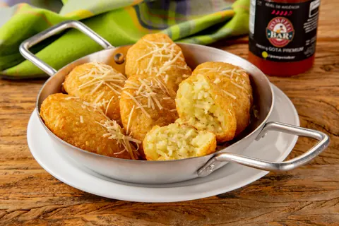 Bolinhos de arroz com parmesão, um deles aberto mostrando o recheio