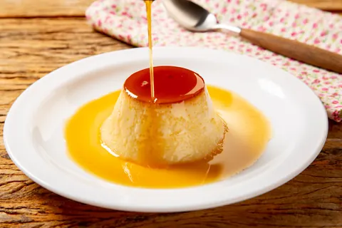 Pudim de leite recebendo calda caramelizada