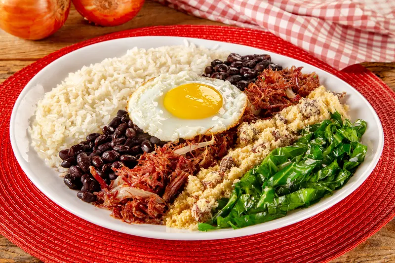 Riscadinho: arroz, feijão preto, carne desfiada, farofa, couve e ovo frito em prato branco